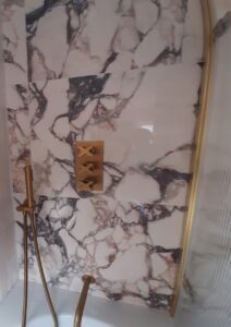 Brass fixtures and textured tiles in small Surrey bathroom renovation by expert fitters.